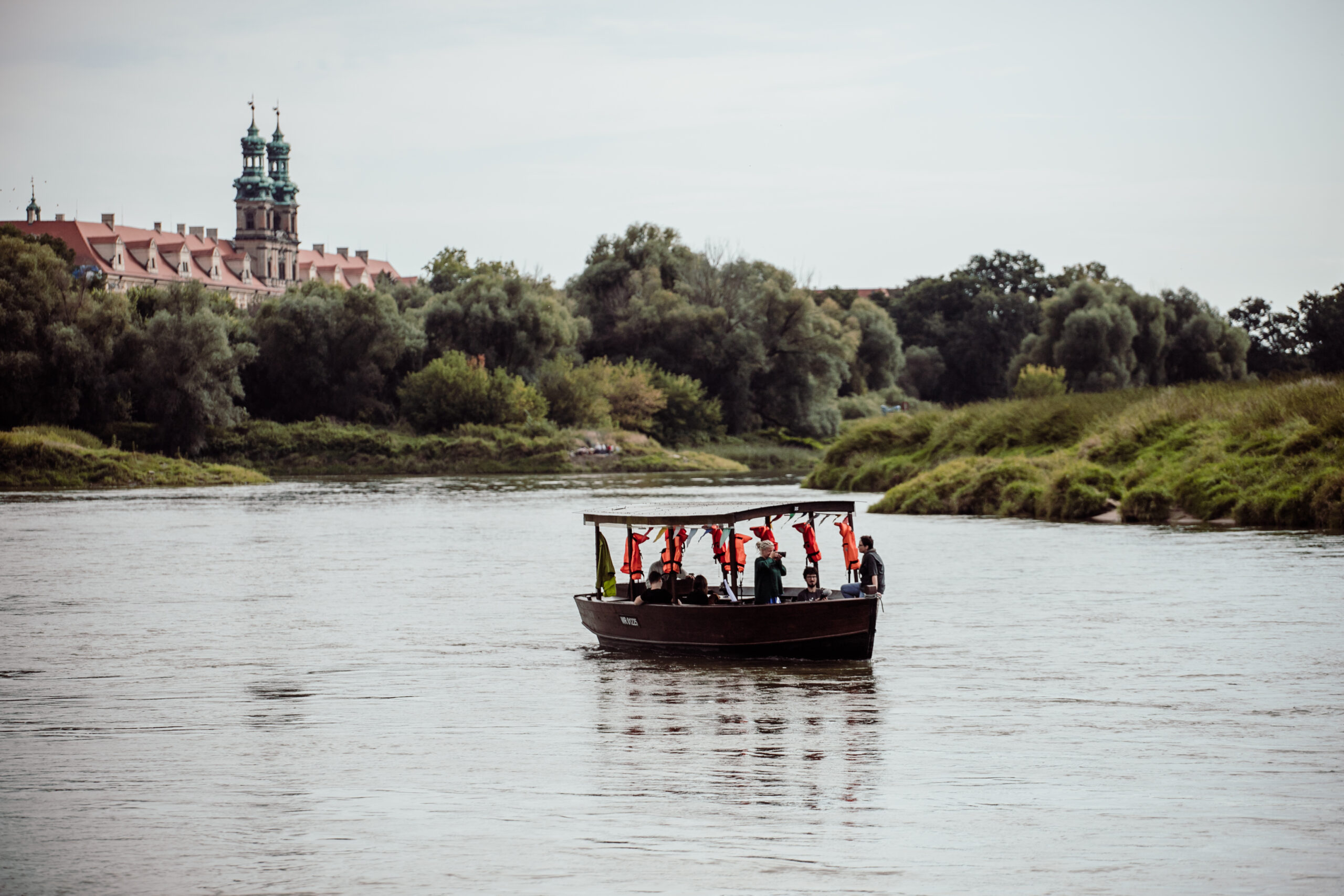 Szkuta płynie Odrą w pobliżu Lubiąża. W oddali klasztor 